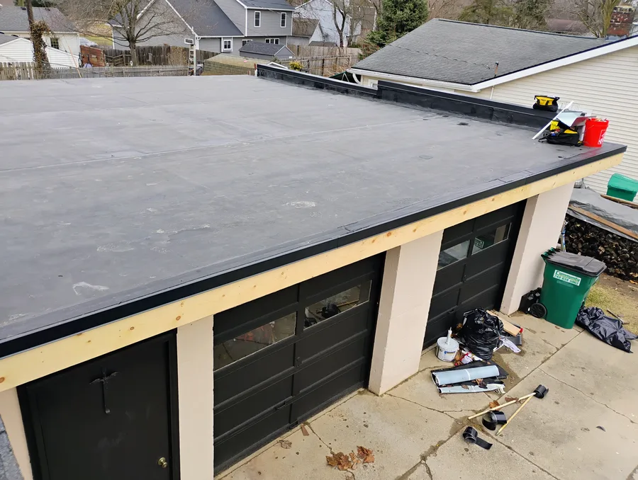 Completed EPDM rubber roof on residential garage, overhead view showing clean black membrane and perimeter trim