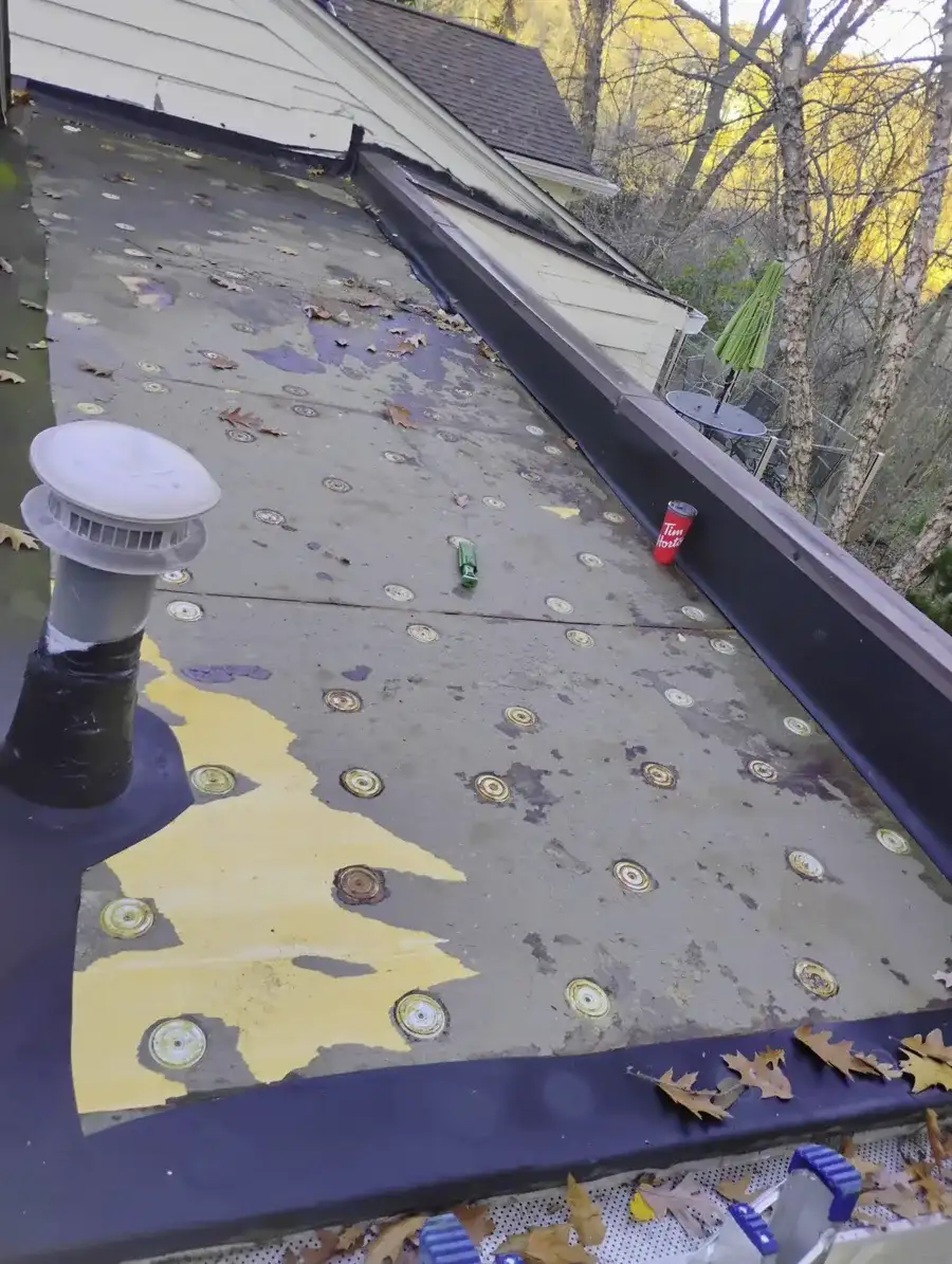 Deteriorated flat roof membrane with exposed fasteners before replacement
