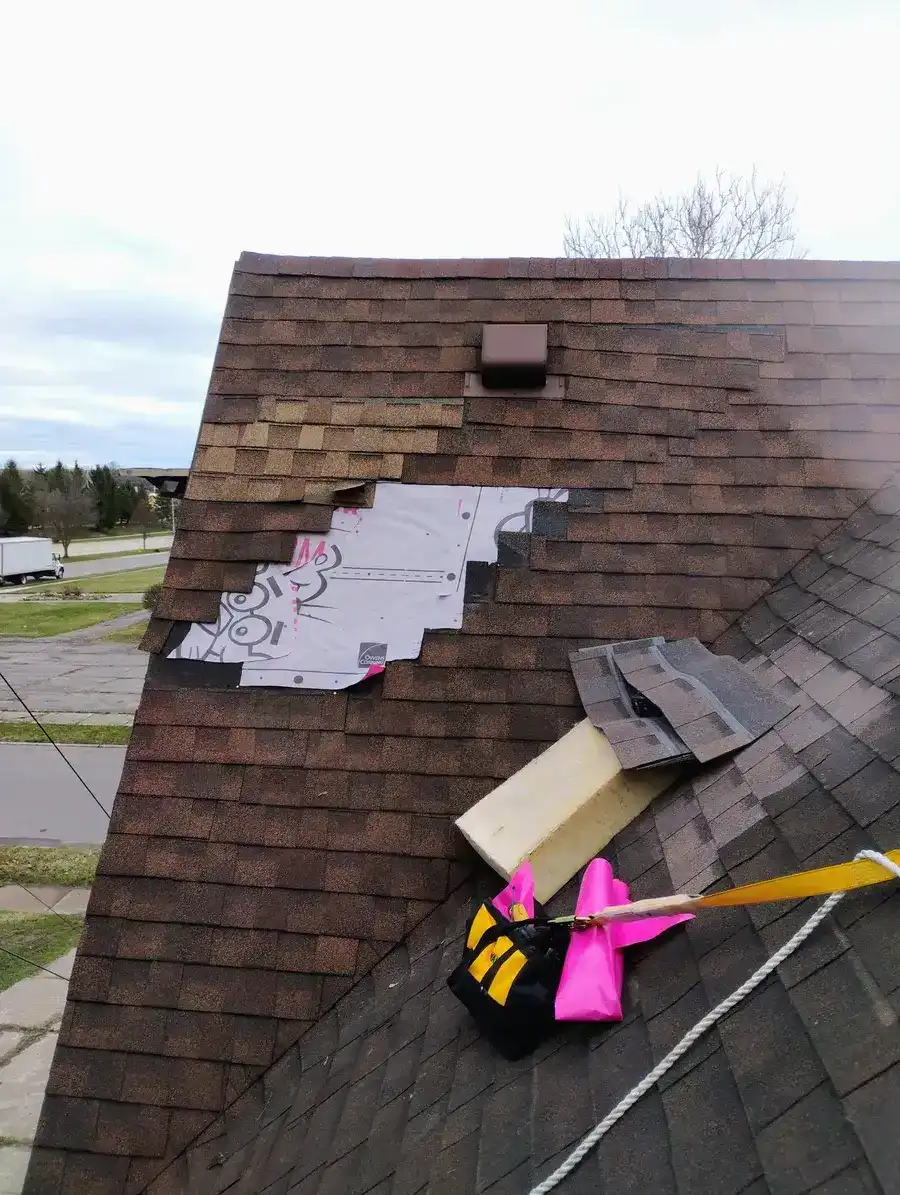 Storm damaged shingle roof with missing shingles and exposed underlayment, emergency repair assessment